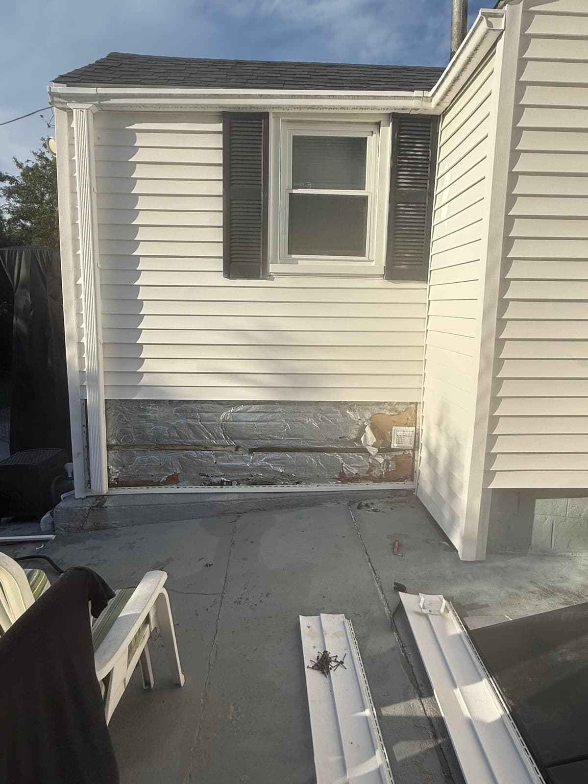 The damaged panel out at the patio corner, insulation board exposed beneath.